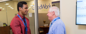 Two businessmen shake hands in front of the GoodWork Staffing office